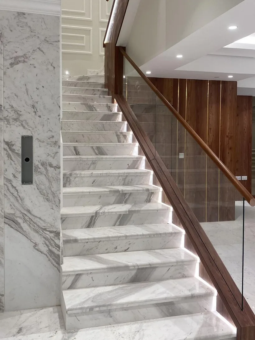 Marble staircase with a walnut handrail and glass balustrade